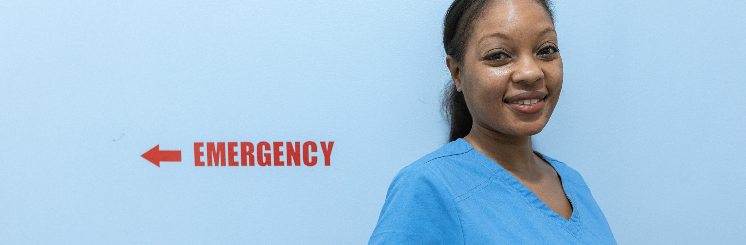 Emergency Nurse beside sign